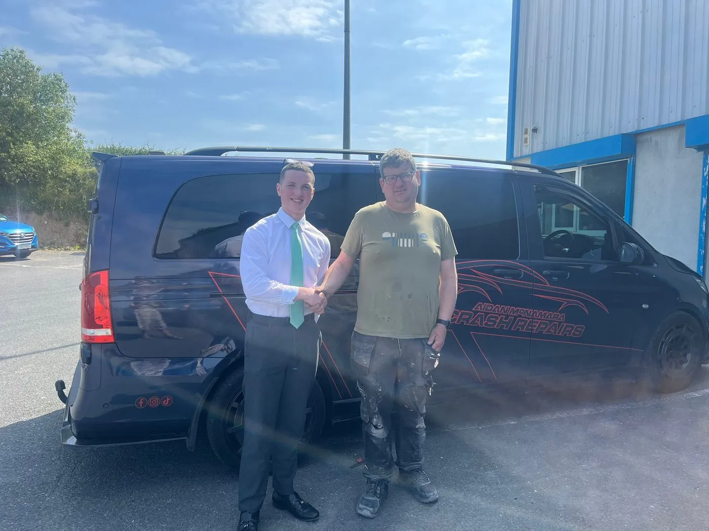 Dylan shaking hands with Aidan McNamara beside his branded van